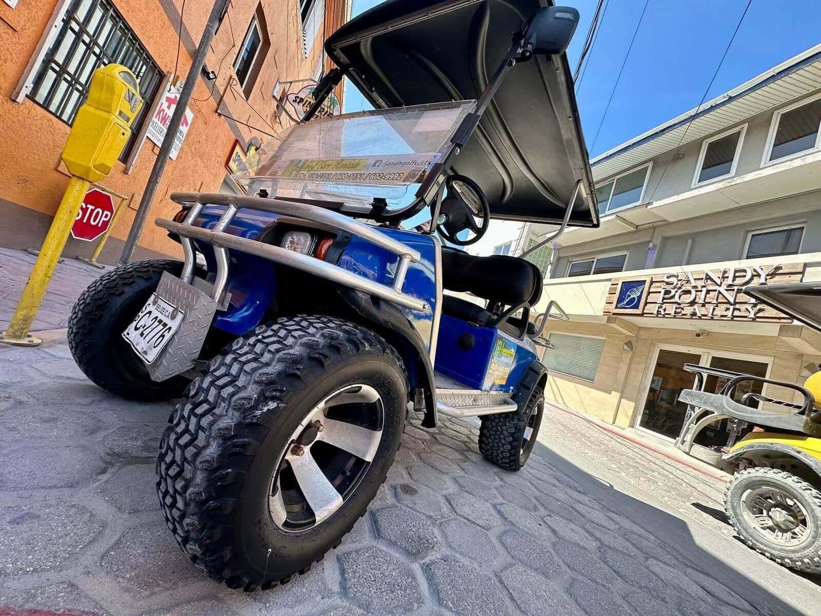 Lifted J and H golf cart parked on a San Pedro cobblestone street