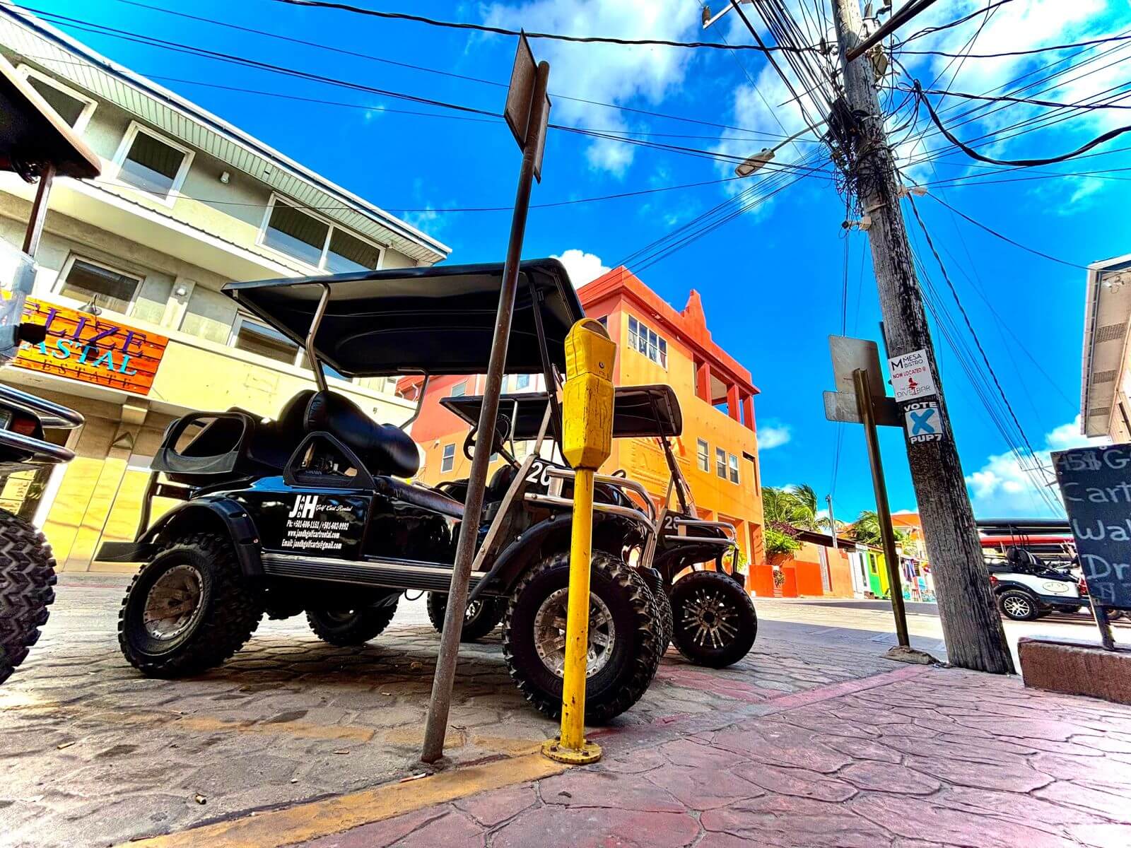 Black lifted golf cart with a bright blue Belize sky behind it