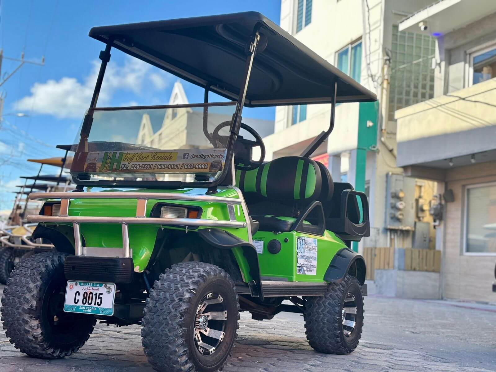 Green golf cart rental on a San Pedro street