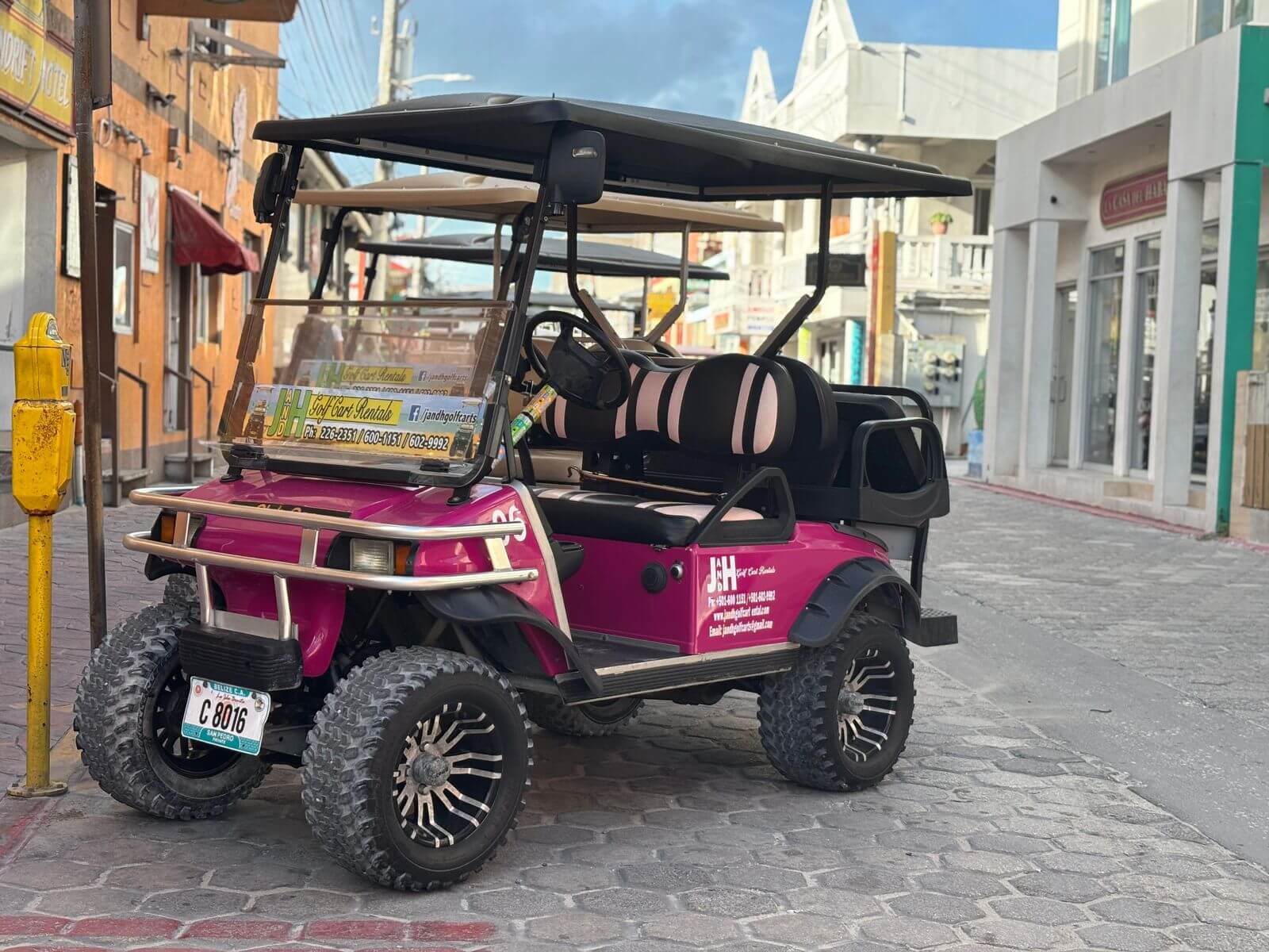 Pink golf cart rental on a paver street in San Pedro, Belize